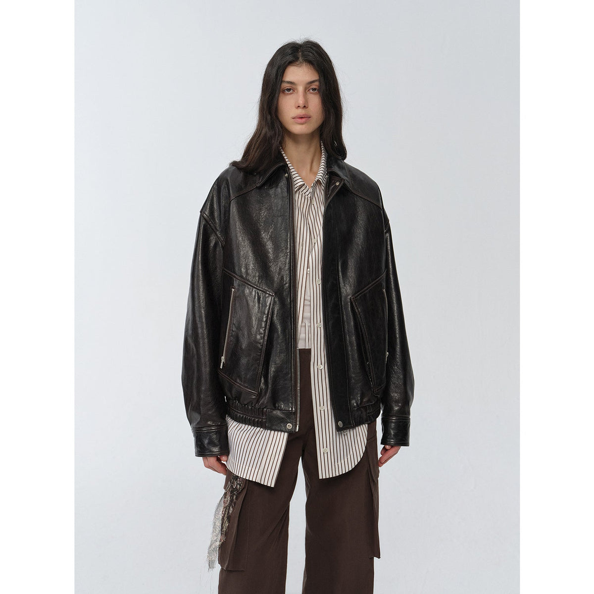 "New York Student" black waxed leather bomber jacket worn over a striped shirt — front view